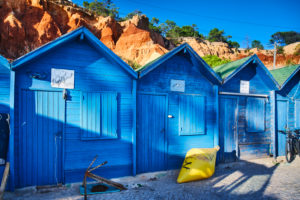 Europa, Portugal, Algarve, Litoral, Barlavento, Distrikt Faro, bei Albufeira, Praia dos Olhos de Agua, blaue Fischerhütten vor rotbrauner Steilküste Europa, Portugal, Algarve, Litoral, Barlavento, Distrikt Faro, bei Albufeira, Praia dos Olhos de Agua, blaue Fischerhütten vor rotbrauner Steilküste
